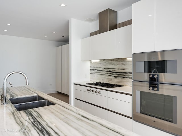 kitchen with white cabinets, sink, tasteful backsplash, stainless steel double oven, and gas cooktop