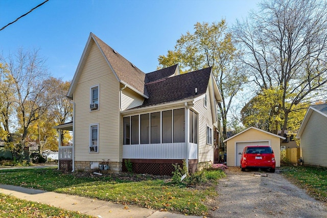 view of front facade featuring a front yard, a garage, an outdoor structure, and a sunroom