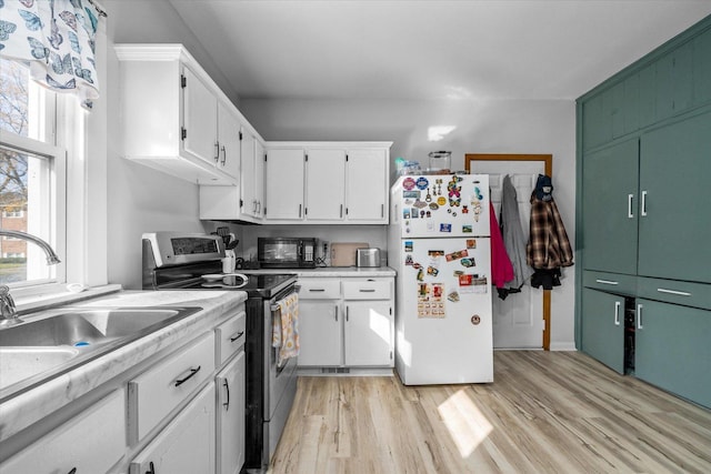 kitchen featuring white cabinets, white fridge, a wealth of natural light, and stainless steel range with electric cooktop