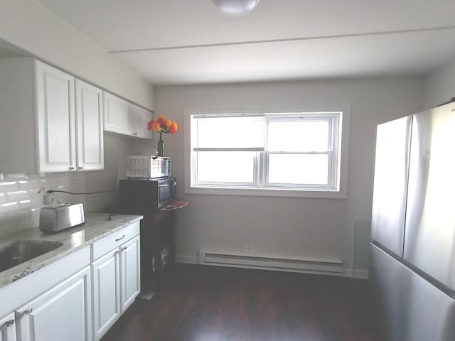 kitchen with white cabinets, plenty of natural light, baseboard heating, and stainless steel refrigerator