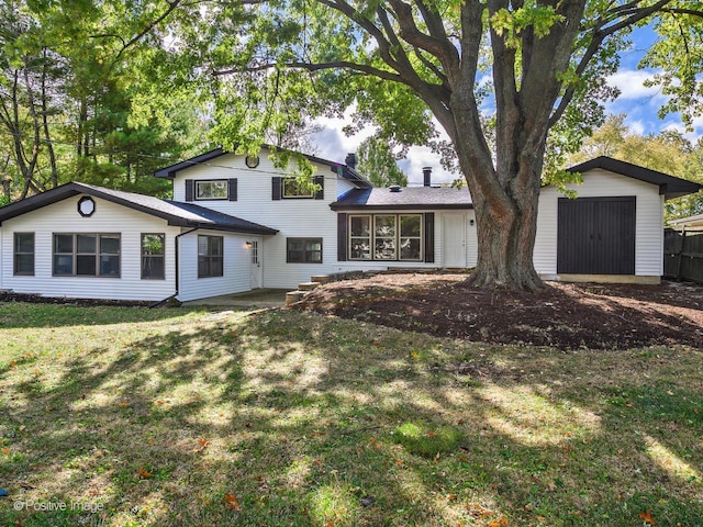 tri-level home featuring a front lawn and a storage shed