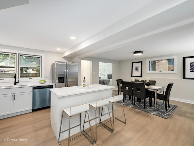 kitchen featuring white cabinetry, sink, a center island, stainless steel appliances, and light wood-type flooring