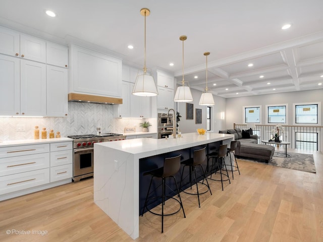 kitchen featuring coffered ceiling, a center island with sink, high end stainless steel range, beamed ceiling, and white cabinets