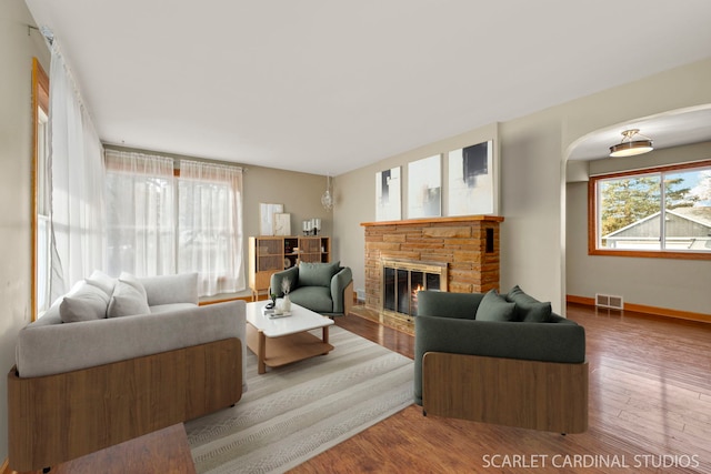 living room featuring a stone fireplace and hardwood / wood-style flooring