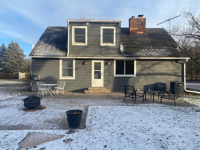 snow covered house with a fire pit and central AC unit