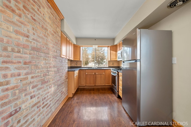 kitchen with dark hardwood / wood-style flooring, stainless steel appliances, brick wall, and sink