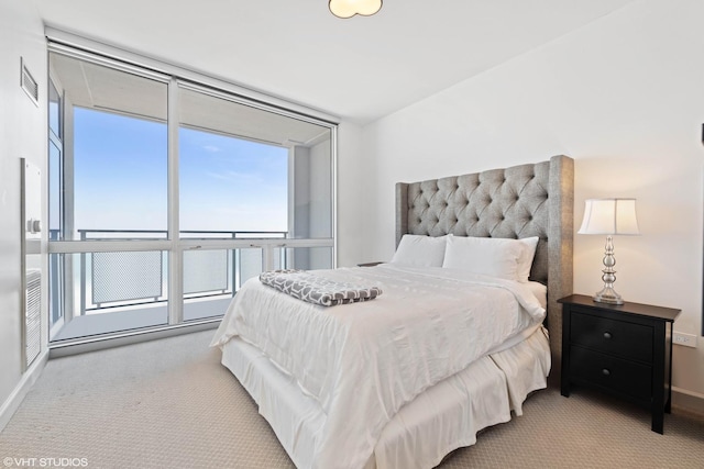 bedroom with light colored carpet, a wall of windows, and multiple windows