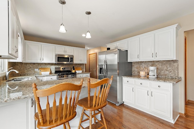 kitchen with stainless steel appliances, a sink, white cabinetry, and light wood-style floors