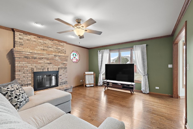 living room with a brick fireplace, light hardwood / wood-style flooring, ceiling fan, and ornamental molding