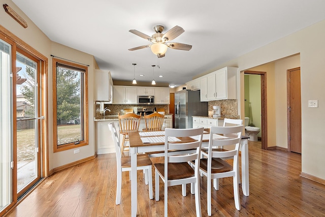 dining area with light wood-style flooring, baseboards, and a ceiling fan