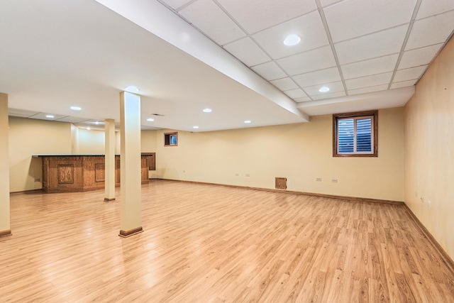 basement with a drop ceiling and light hardwood / wood-style flooring