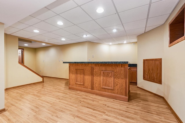 bar with light wood-style flooring, baseboards, bar area, and a drop ceiling