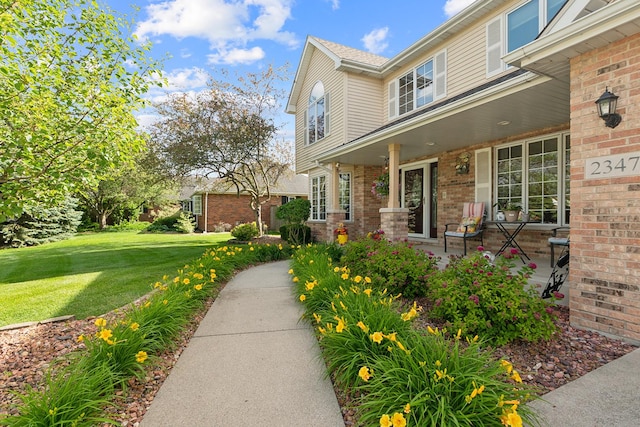 entrance to property with a lawn and brick siding