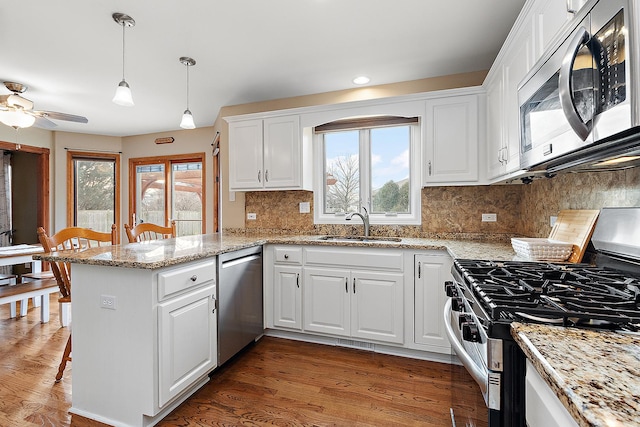 kitchen with white cabinetry, sink, hanging light fixtures, kitchen peninsula, and appliances with stainless steel finishes