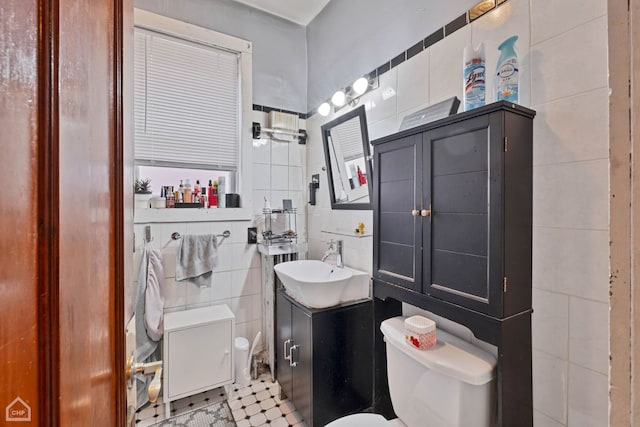 bathroom with vanity, toilet, and tile walls