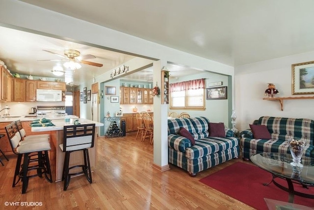 living room featuring ceiling fan, light hardwood / wood-style floors, and sink