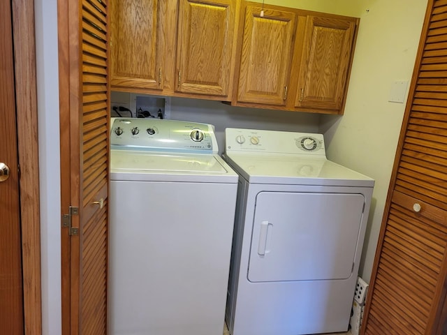 clothes washing area with cabinets and washer and clothes dryer