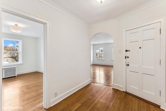 foyer with radiator, ornamental molding, and hardwood / wood-style floors