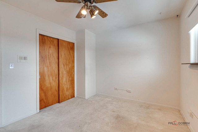 unfurnished bedroom with light carpet, a closet, and ceiling fan