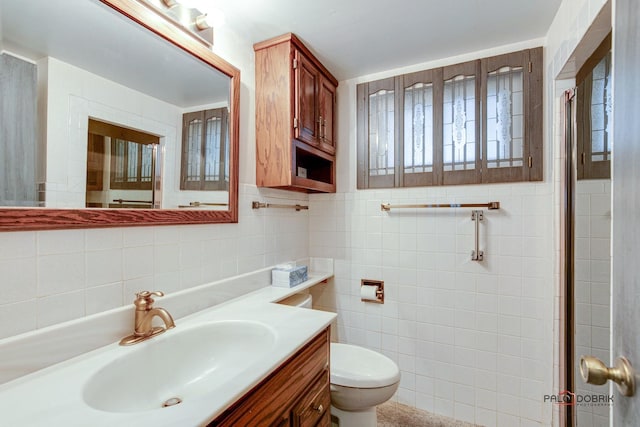 bathroom featuring vanity, tile walls, and toilet