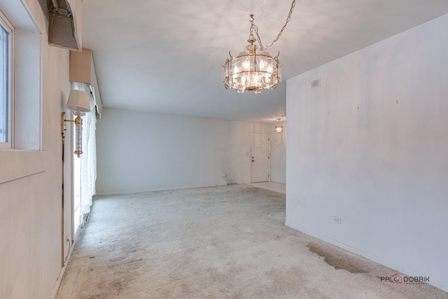 carpeted empty room featuring an inviting chandelier and plenty of natural light