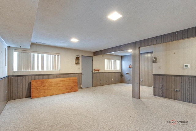 basement featuring a textured ceiling, carpet floors, and a healthy amount of sunlight