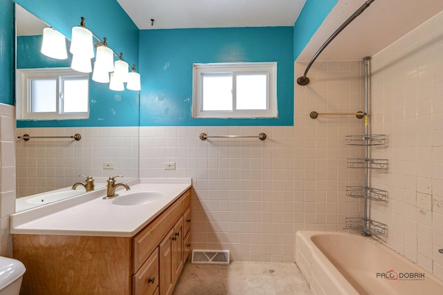 full bathroom with tiled shower / bath combo, toilet, tile walls, and vanity