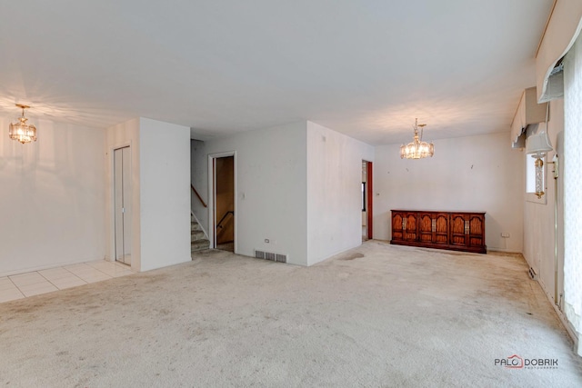 spare room with light colored carpet and a notable chandelier