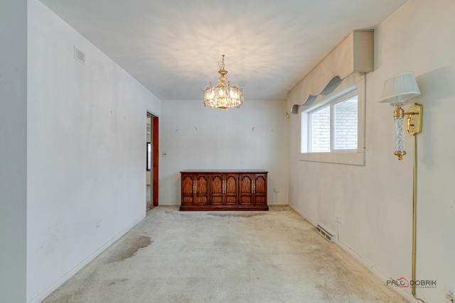 carpeted empty room with a chandelier