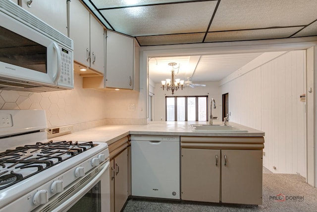 kitchen with white appliances, white cabinets, sink, decorative light fixtures, and a chandelier