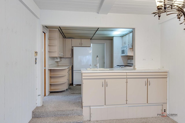 kitchen with wood walls, beam ceiling, white appliances, and sink