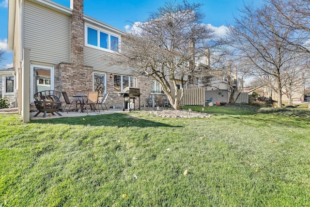 rear view of house with a lawn, an outdoor fire pit, and a patio