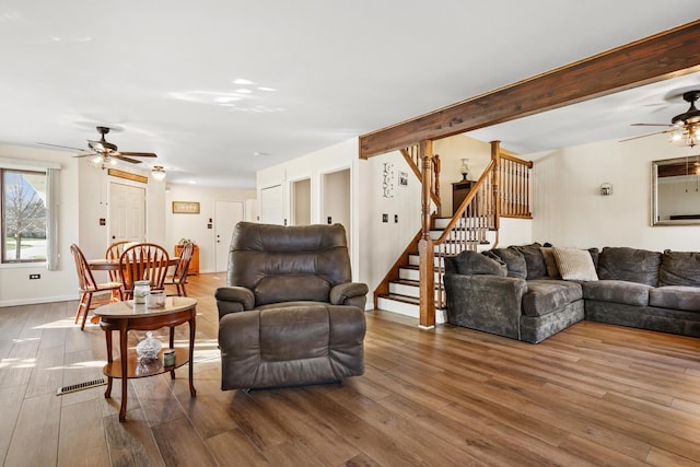 living room with hardwood / wood-style floors, ceiling fan, and beamed ceiling