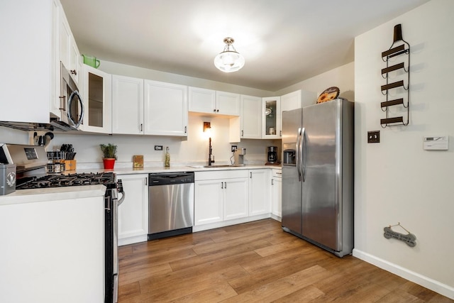 kitchen featuring white cabinets, appliances with stainless steel finishes, light hardwood / wood-style floors, and sink