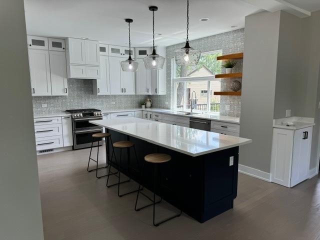 kitchen featuring a center island, white cabinetry, a breakfast bar area, and gas stove