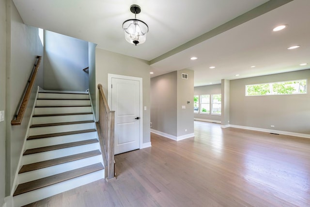 staircase featuring hardwood / wood-style floors and a notable chandelier