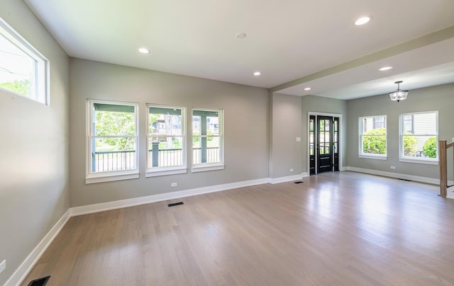 unfurnished room featuring light wood-type flooring, plenty of natural light, and a notable chandelier