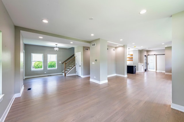 unfurnished living room with hardwood / wood-style flooring and a barn door