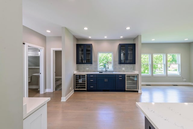 kitchen with decorative backsplash, light wood-type flooring, beverage cooler, and sink