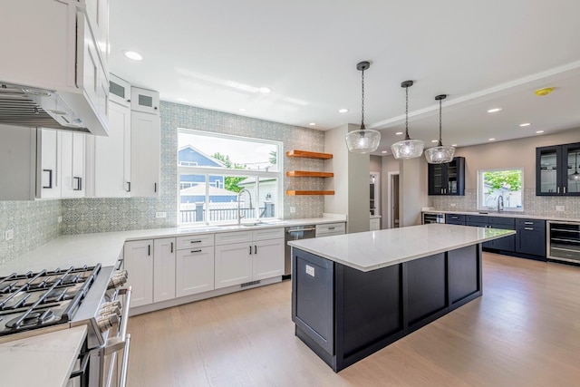 kitchen featuring light stone countertops, a kitchen island, wine cooler, white cabinets, and appliances with stainless steel finishes