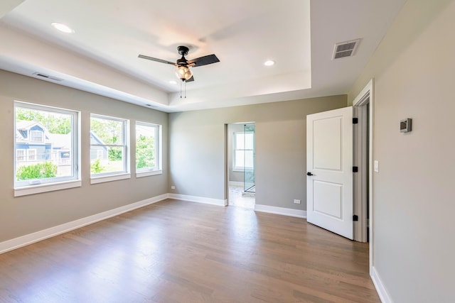 unfurnished room featuring a raised ceiling, ceiling fan, and wood-type flooring