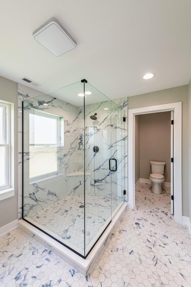 bathroom featuring toilet and a shower with door