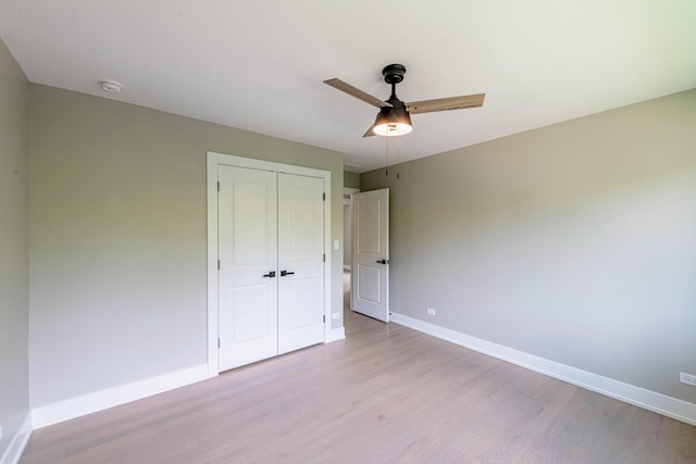 unfurnished bedroom featuring ceiling fan, a closet, and light wood-type flooring