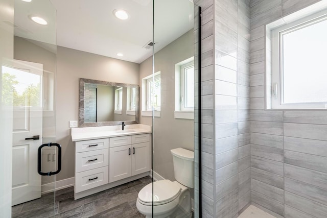 bathroom with walk in shower, vanity, and toilet