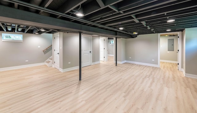 basement featuring electric panel and light hardwood / wood-style floors