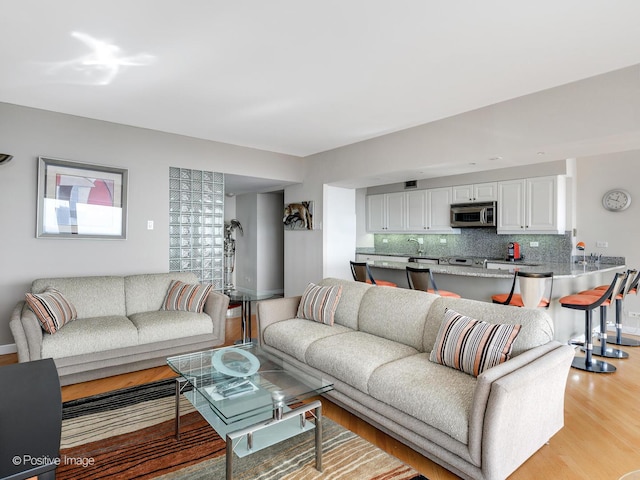 living room featuring sink and light hardwood / wood-style flooring