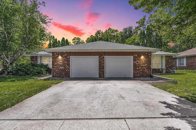 single story home with a garage, a lawn, and driveway