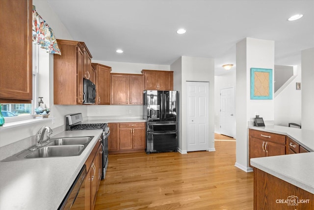 kitchen featuring black appliances, light hardwood / wood-style floors, and sink