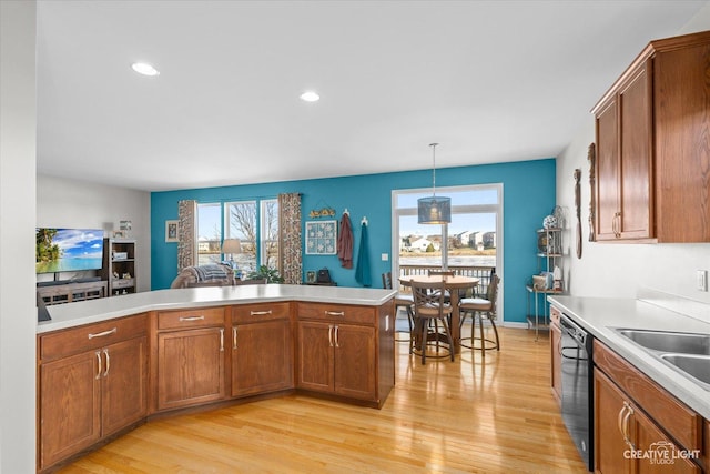 kitchen with pendant lighting, sink, black dishwasher, light hardwood / wood-style floors, and kitchen peninsula