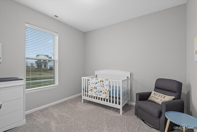 bedroom with multiple windows, light colored carpet, and a crib